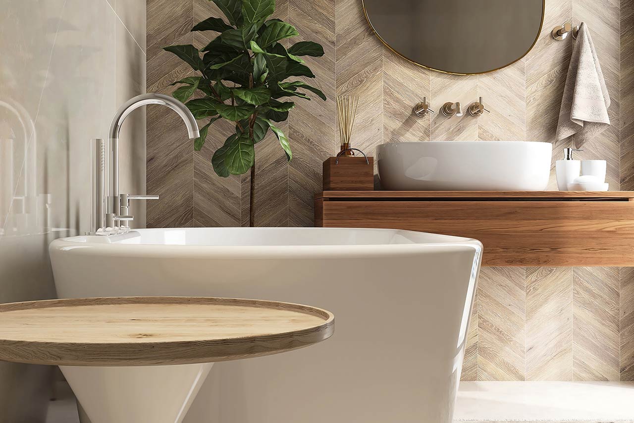 Round wooden side table, bathtub, fiddle leaf fig tree in luxury design bathroom in sunlight on beige brown tile wall